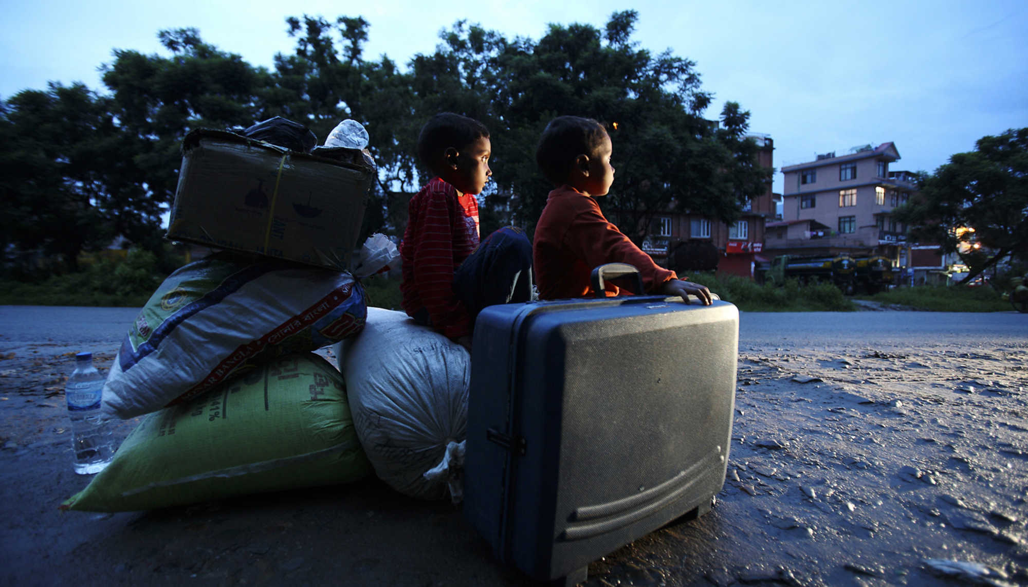 Nepalesische Flüchtlingskinder sitzen nach dem Bürgerkrieg auf den Habseligkeiten der Familie auf der Straße.