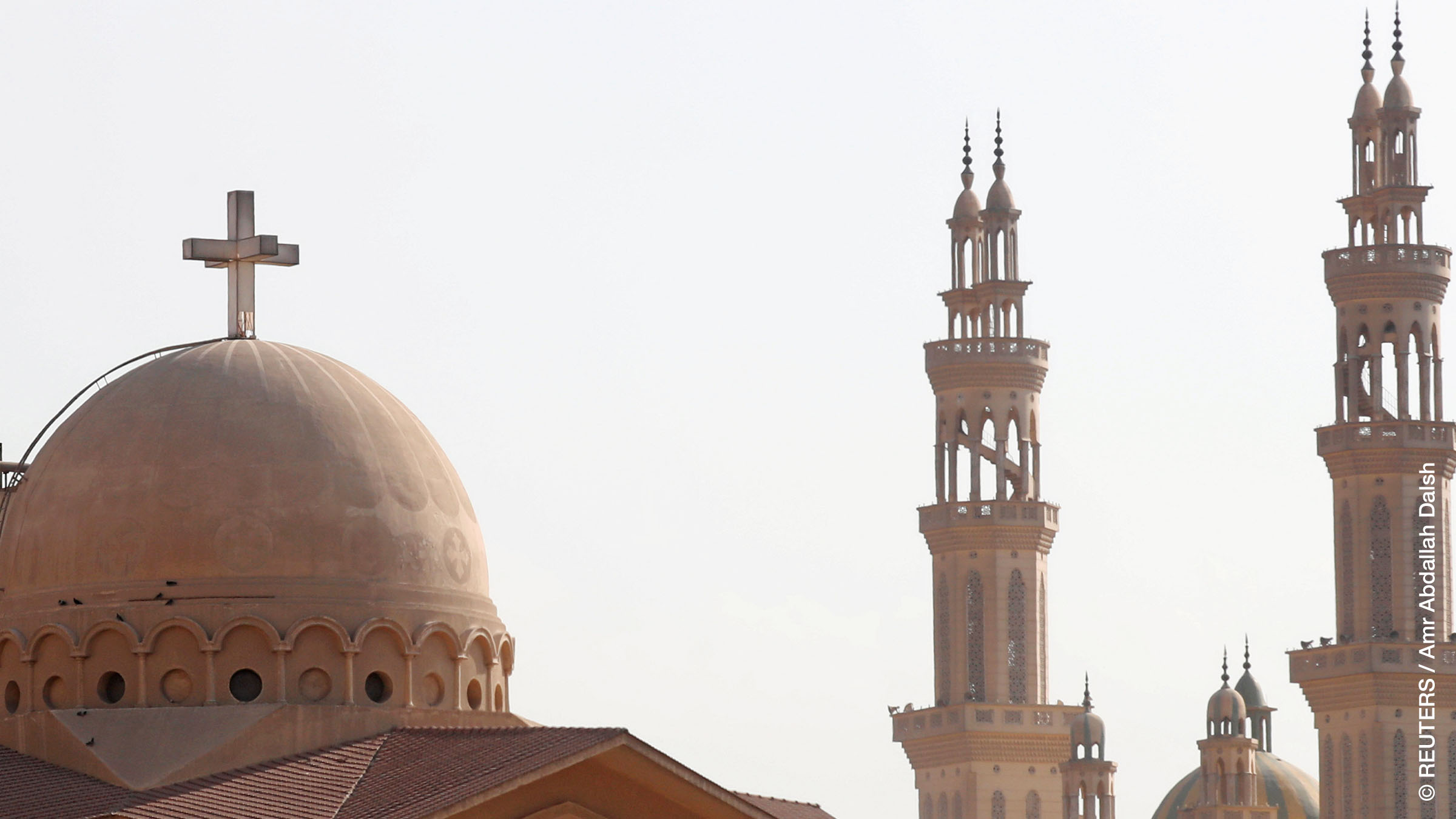 Minarets of a mosque and the cross above a church is seen during the Muslim holy fasting month of Ramadan, in the El-Marg district of Cairo, Egypt June 13, 2018. 