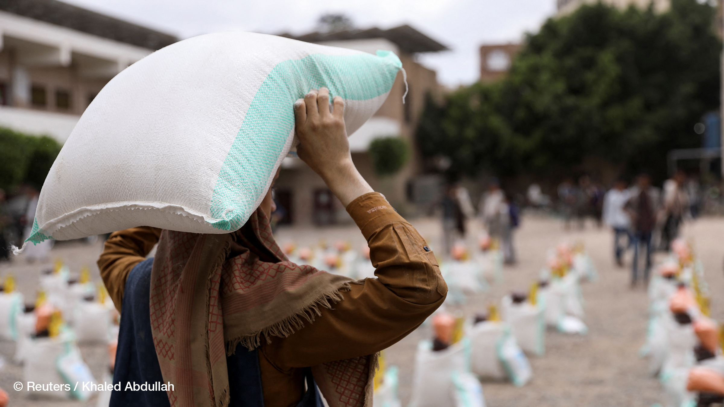 A worker carries a sack of wheat flour during the distribution of food aid by the local charity, Mona Relief, in Sanaa, Yemen April 24, 2022.